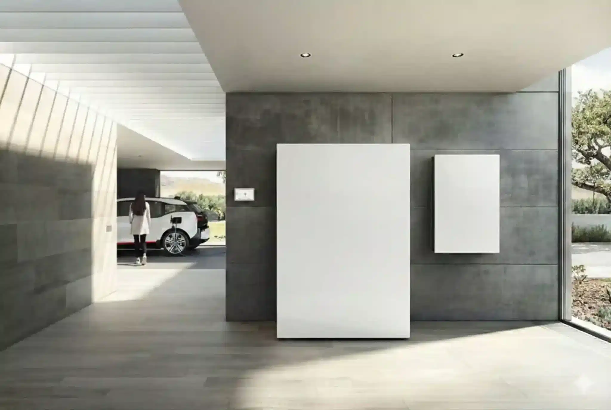 Domácí bateriová úložiště na zdi a tesla vzadu